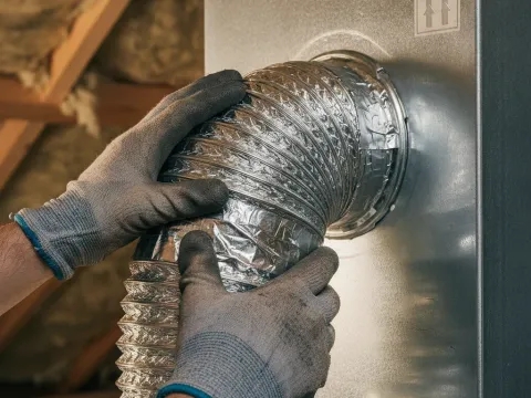 Technician connects ventilation ductwork during an ERV install in an Aubrey home