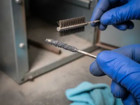 Close-up of dirty flame sensor being cleaned during furnace maintenance in Providence Village